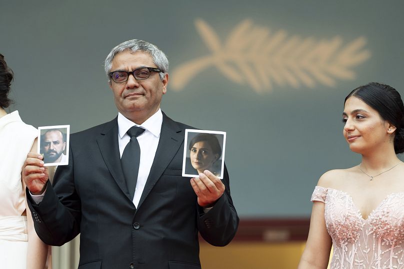 Mohammad Rasoulof holds photographs of actors Missagh Zareh and Soheila Golestani at the premiere of 'The Seed of the Sacred Fig'