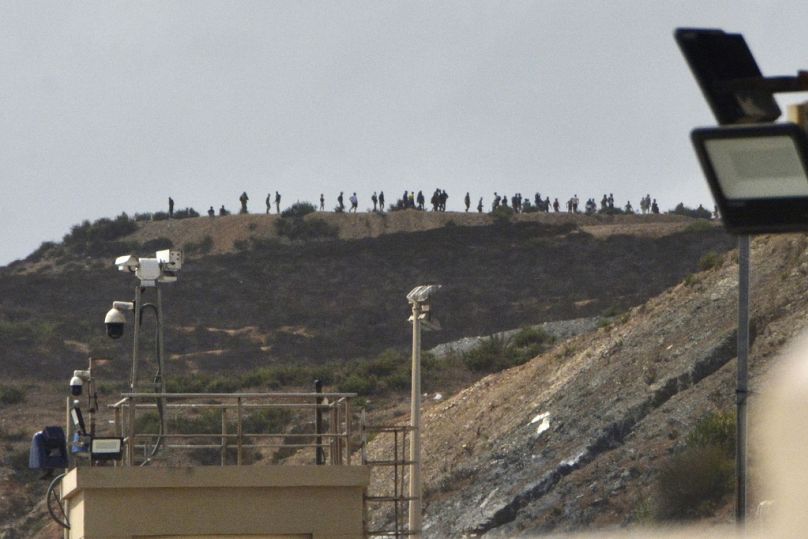 Des migrants se tiennent au sommet d'une colline à la frontière de Tarajal dans l'enclave espagnole de Ceuta. 