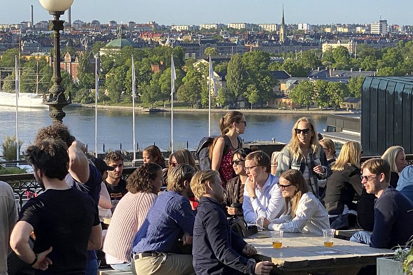 People enjoy drinks and snacks in the evening sun on a terrace overlooking Stockholm in 2023. Smoking is prohibited in outdoor areas of bars and restaurants in Sweden.