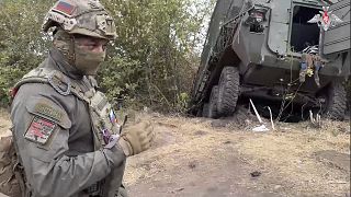 Un soldat russe se tient à côté d'un véhicule ukrainien endommagé dans la région de Koursk, en Russie, le vendredi 13 septembre 2024 (ministère russe de la Défense via AP).