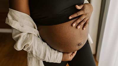 A woman holds a pregnant stomach.