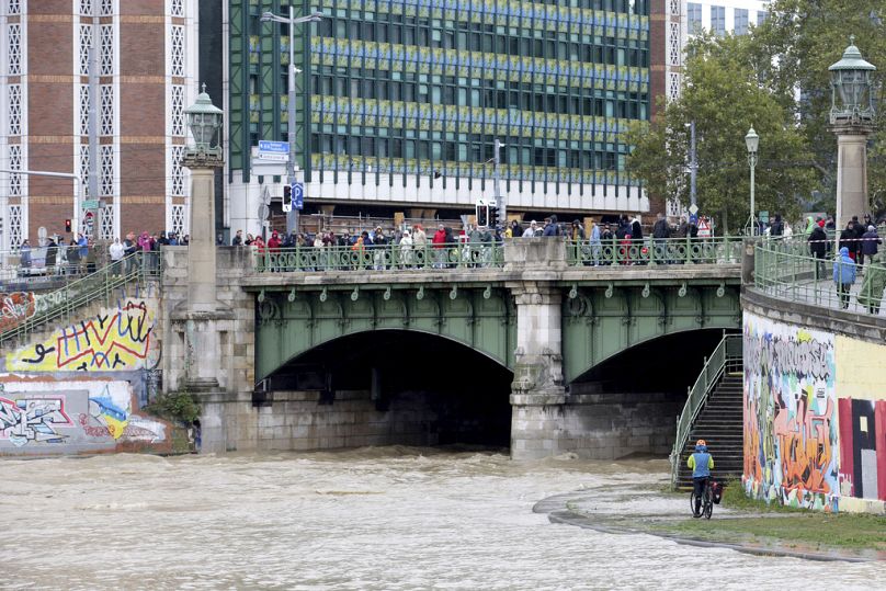 People watch the junction of river Wien and Donaukanal channel as they flood their banks in central Vienna, Austria, Sunday, Sept. 15, 2024.