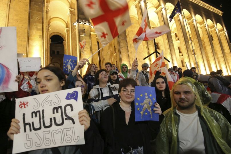 Des manifestants avec des drapeaux de la Géorgie et de l'UE, l'un d'entre eux portant l'affiche « Pas de loi russe », en mai 2024