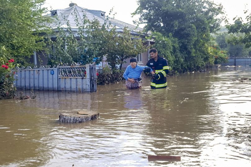 Um bombeiro ajuda uma mulher a sair de casa na aldeia de Pechea, a 14 de setembro de 2024