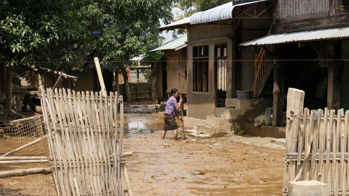 Una donna cerca di ripulire una casa danneggiata da un'inondazione a Naypyitaw, Myanmar