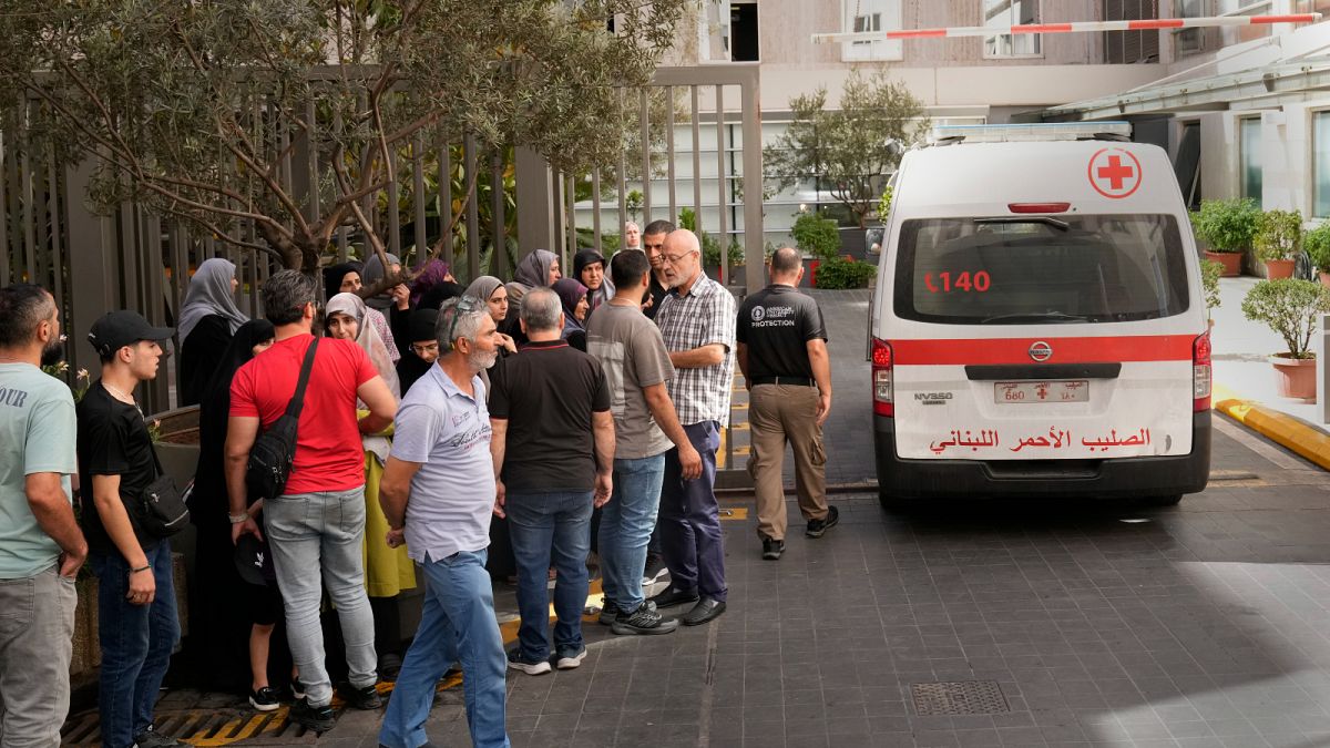 Una ambulancia de la Cruz Roja Libanesa pasa junto a los familiares de las víctimas heridas por la explosión de sus localizadores portátiles.