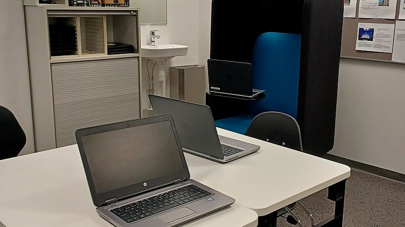 Prisoners participating in AI work sit in trio in a room. The work is typically for three hours with a break.