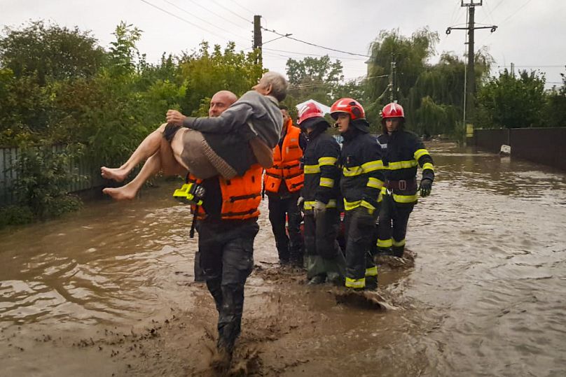 Un secouriste porte un vieil homme touché par les inondations à Pechea en Roumanie 