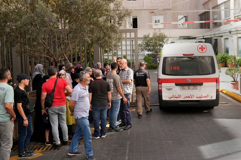 سيارة إسعاف تابعة للصليب الأحمر تمر بجانب أهالي الضحايا الذين أصيبوا  بانفجار جهاز النداء المحمول باليد، مستشفى الجامعة الأميركية في بيروت، الأربعاء 18 سبتمبر/أيلول 2024