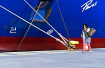 A passenger walks past a docked ship during a 48-hour strike in the port of Piraeus, near Athens, Greece, 