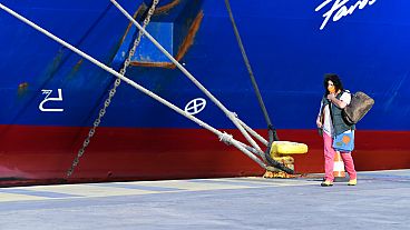 A passenger walks past a docked ship during a 48-hour strike in the port of Piraeus, near Athens, Greece, 