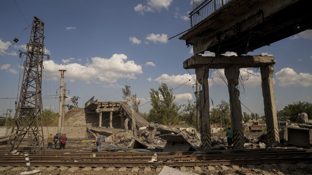 Railway workers look on the bridge destroyed by a Russian airstrike in Pokrovsk, Ukraine