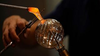 A glass-worker finishes a glass artistic creation in a factory in Murano island, Venice, Italy, Thursday, Oct. 7, 2021.