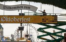 Workers stand on a lifting platform during construction work on the Oktoberfest grounds at the festival's main entrance in Munich, Germany