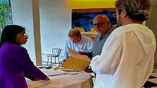 Delcy Rodríguez y Jorge Rodríguez junto a Edmundo González mientras este firma un documento en la Emabajada de España en Caracas. 