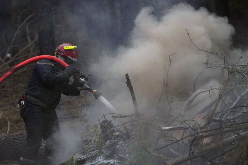 Um bombeiro pulveriza água para apagar os restos de um incêndio numa floresta ardida, em Hostens, a sul de Bordéus, no sudoeste de França.