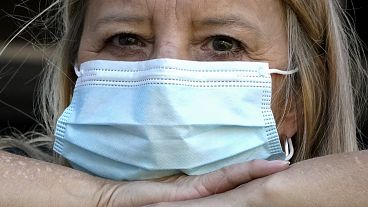 FILE - A woman wears a mask at her home after previously having COVID.