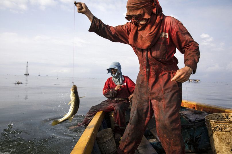 Fishermen wearing oil stained uniforms from Venezuela's state-run oil firm PDVSA, catch bass known as "robalo" near La Salina crude oil shipping terminal, on Lake Maracaibo ne