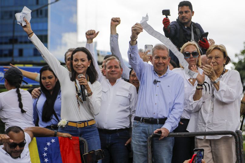 La líder opositora María Corina Machado, a la izquierda, y el candidato opositor Edmundo González sostienen actas del escrutinio desde lo alto de un camión en una protesta