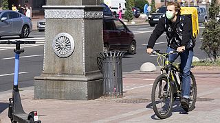 A delivery cyclist wearing a face mask cycles down a street in Kyiv, Ukraine, Friday Sept. 20, 2024