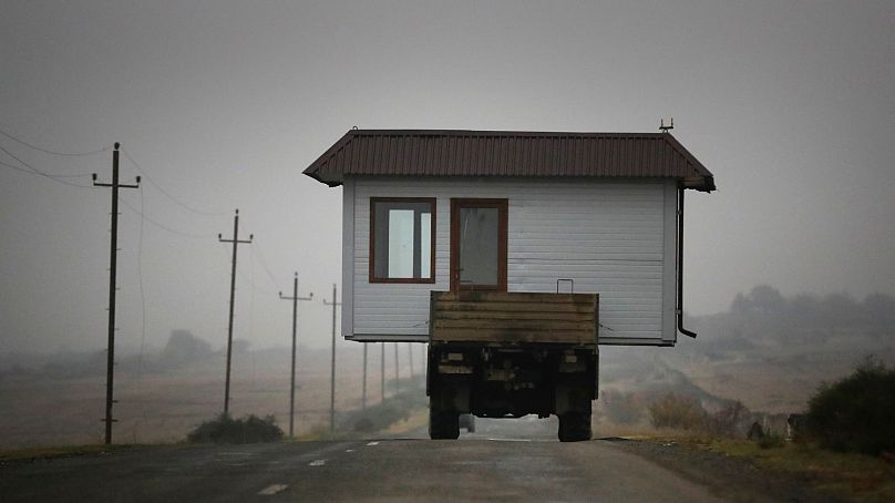 An Armenian family drives a truck loaded with a small house along a highway as they leave their home village in Nagorno-Karabakh, 18 November 2020.