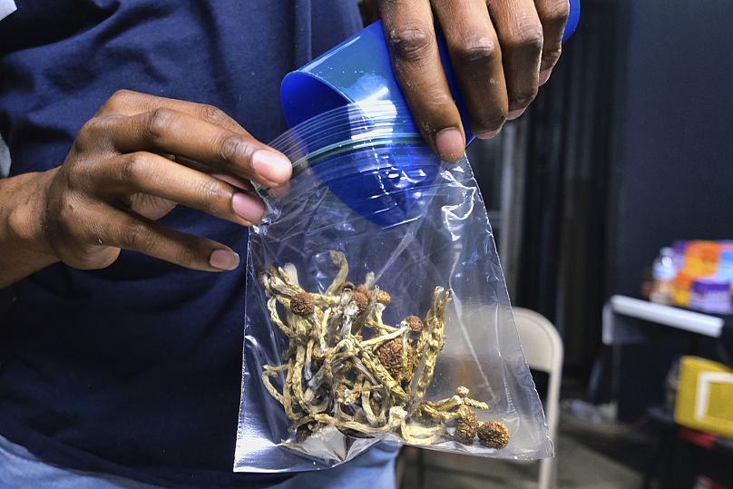 A vendor bags psychedelic mushrooms at a marketplace in the US.