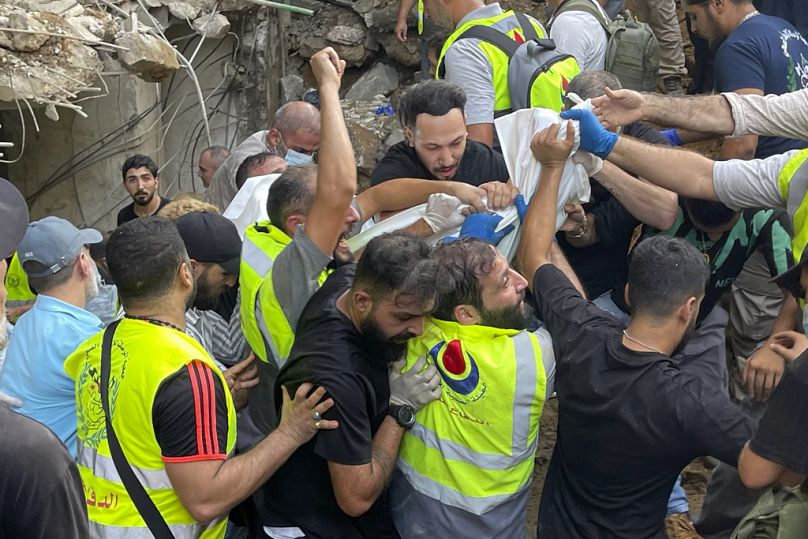 Rescuers carry a body at the scene of a missile strike in the southern suburbs of Beirut, Friday, Sept. 20, 2024