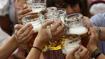 Os visitantes levantam as suas canecas de cerveja na tenda Hofbraeuhaus após a abertura do famoso festival de cerveja bávaro "Oktoberfest" numa tenda de cerveja em Munique.