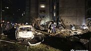 People mill around damaged cars and debris after a Russian strike on a residential building in Kharkiv, Ukraine early Sunday Sept. 22, 2024.