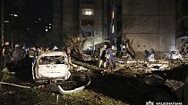 People mill around damaged cars and debris after a Russian strike on a residential building in Kharkiv, Ukraine early Sunday Sept. 22, 2024.