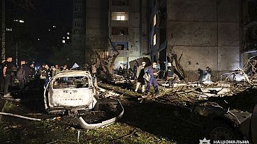 People mill around damaged cars and debris after a Russian strike on a residential building in Kharkiv, Ukraine early Sunday Sept. 22, 2024.