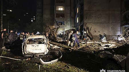 People mill around damaged cars and debris after a Russian strike on a residential building in Kharkiv, Ukraine early Sunday Sept. 22, 2024.