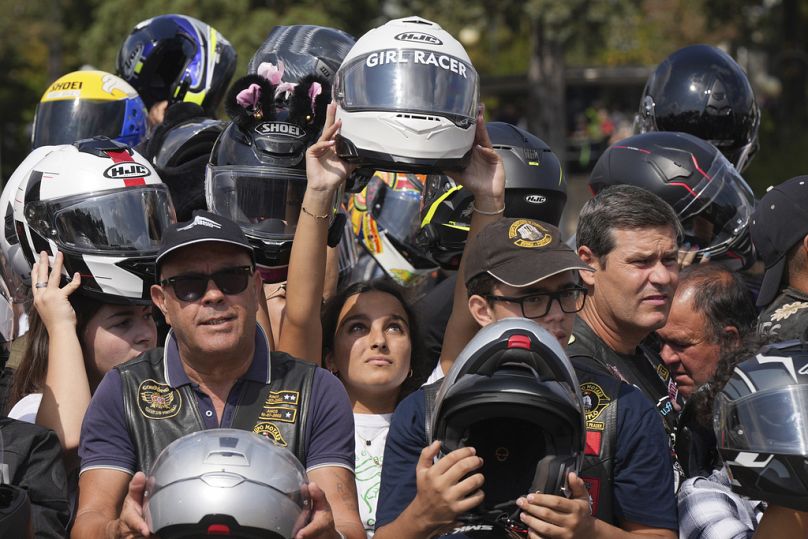 Des fidèles brandissent leur casque pour le faire bénir lors du IXe pèlerinage de bénédiction des casques. 