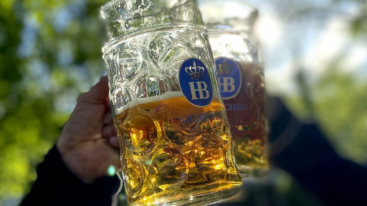 Persone brindano con i loro boccali di birra nella birreria "Taxisgarten" di Monaco.