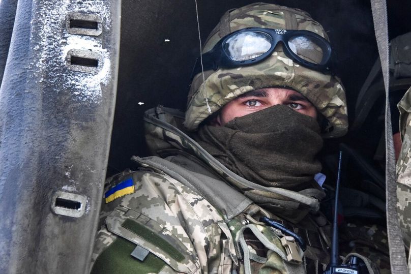 Ukrainian soldier looks down from a military truck at pro-Russian rebels during the Ukrainian military rotation of Airport of Donetsk, Eastern Ukraine, Jan. 6, 2015. 