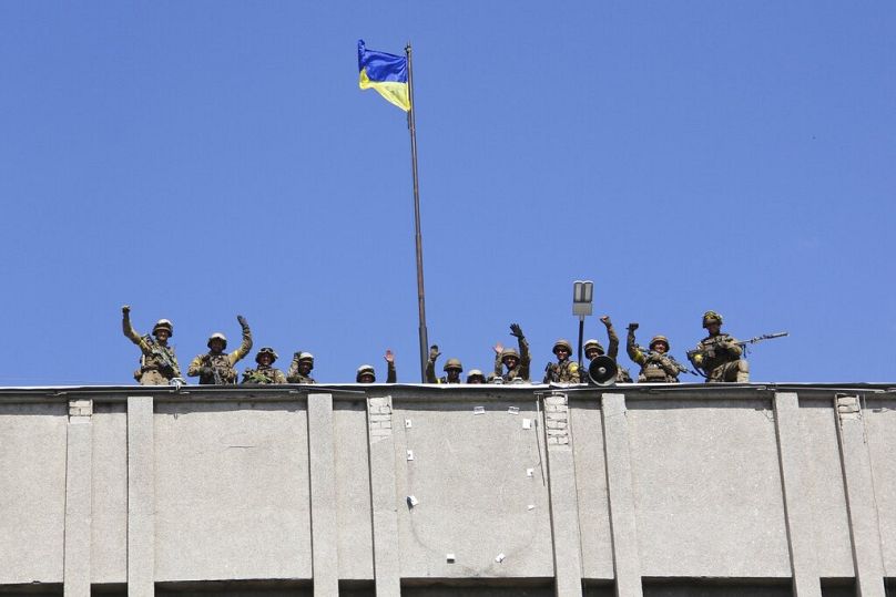 Auf diesem Foto vom Samstag, dem 5. Juli 2014, hissen ukrainische Soldaten eine ukrainische Flagge über dem Sitz der Stadtregierung in der ostukrainischen Stadt Slowjansk.