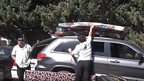 Displaced people load mattresses onto the roof of their car. Displaced people load mattresses onto the roof of their car.