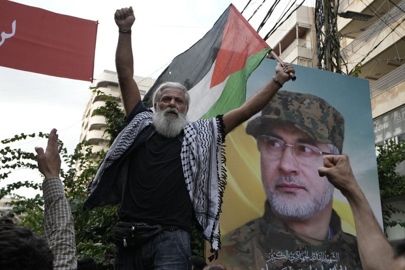 أحد مؤيدي حزب الله يحمل علم فلسطين خلال تشييع جنازة القيادي في حزب الله إبراهيم عقيل، في الضاحية الجنوبية لبيروت، الأحد 22 سبتمبر/أيلول 2024.