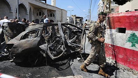 A Lebanese army soldier passes in front a car that was hit by an Israeli strike in the southern port city of Sidon, Lebanon, Wednesday, Aug. 21, 2024. (AP Photo/Mohammad Zaata
