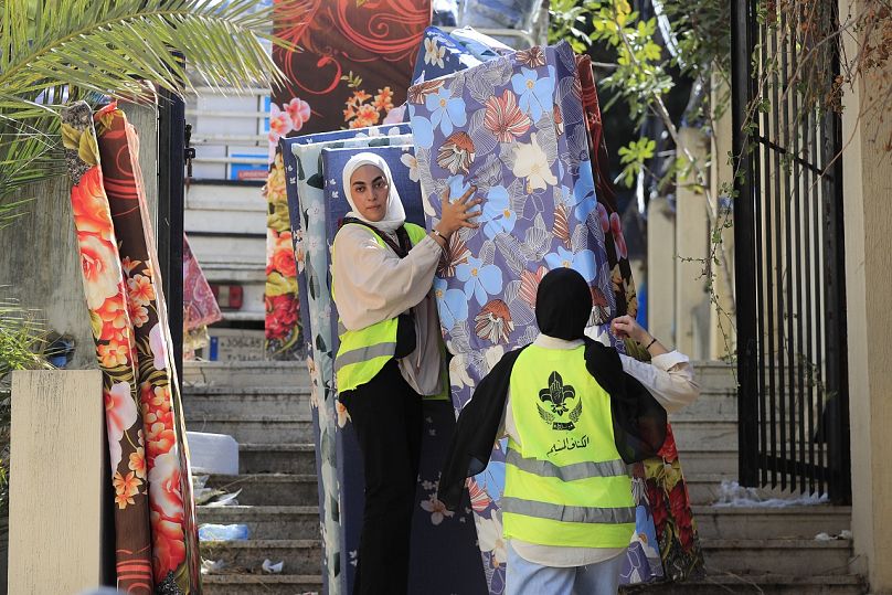 Muslim scout volunteers carry mattresses into a school as people fleeing the Israeli airstrikes in the south take shelter in Sidon, Lebanon, Wednesday, Sept. 25, 2024.