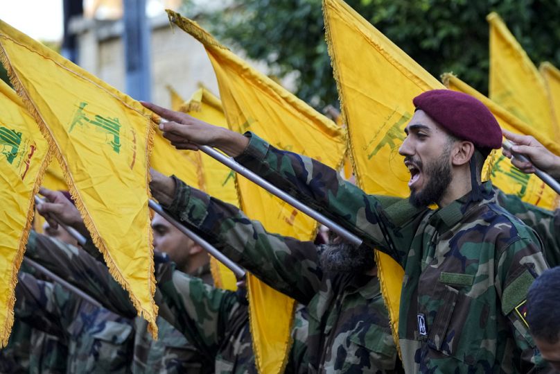 Hizbullah üyeleri Beyrut'ta bayrak kaldırıp slogan atıyor, 25 Eylül 2024.