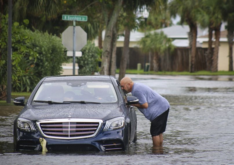 Melvin Juarbe, right, attempts to assist an unidentified driver whose car stalled in floodwaters from Hurricane Helene Thursday, Sept. 26, 2024 in Madeira Beach, Fla.
