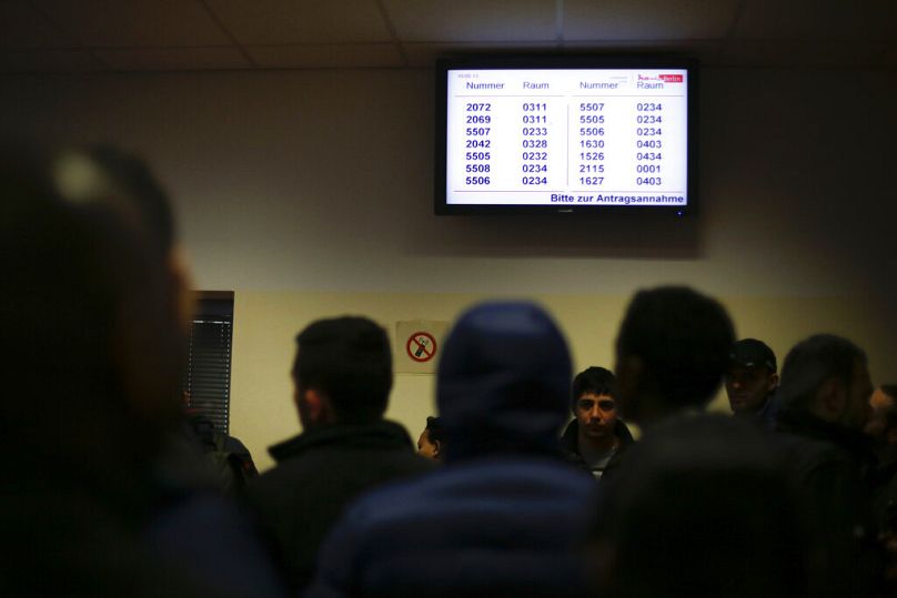 Refugiados esperan frente a una pantalla de información antes de dirigirse a un administrador en el centro de recepción para solicitantes de asilo en Berlín, Alemania 2015.