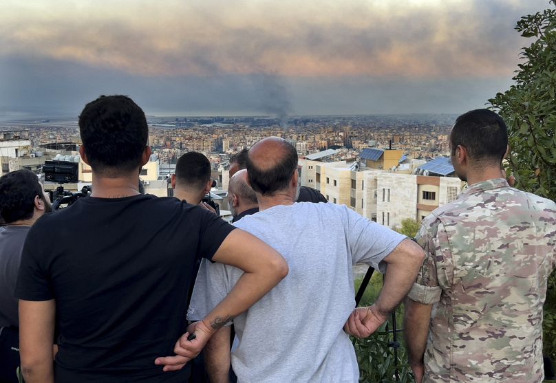 Cidadãos libaneses observam o fumo dos ataques aéreos israelitas nos subúrbios do sul de Beirute, no Líbano, no sábado, 28 de setembro de 2024