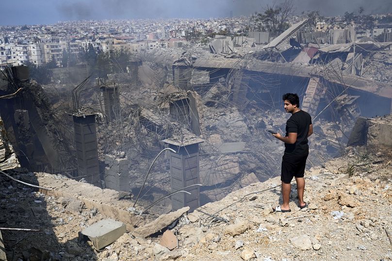 Un homme vérifie un bâtiment endommagé sur le site d'une frappe aérienne israélienne au sud-est de Beyrouth, le 28 septembre 2024.