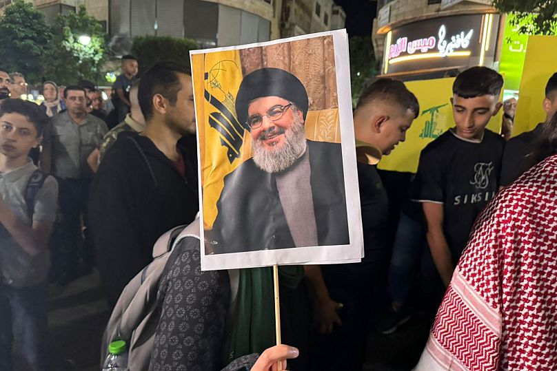 Manifestantes palestinianos carregam bandeiras do Hezbollah e cartazes de Hassan Nasrallah durante uma manifestação de apoio ao Hezbollah em Ramallah, 28 de setembro de 2024