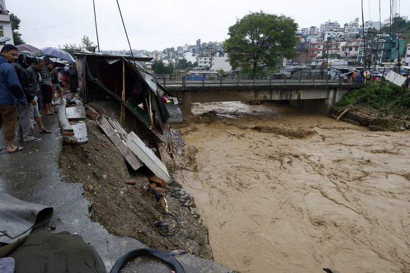 People gather at the edge of the Bagmati River in spate after heavy rains in Kathmandu, Nepal, Saturday, Sept. 28, 2024.