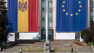 FILE - A woman runs past the government building, decorated with European Union and Moldovan flags in Chisinau, Moldova, on May 31, 2023