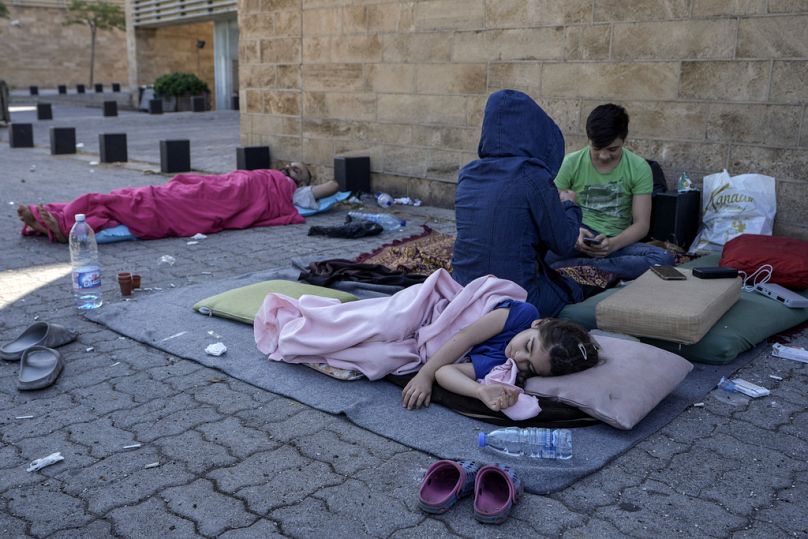 A family sleep on the ground in Beirut's corniche area after fleeing the Israeli airstrikes in the southern suburbs of Dahiyeh, Sunday, Sept. 29, 2024. 