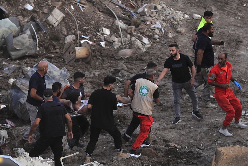 Rescue teams carry an injured man from two adjacent buildings that were hit by an Israeli airstrike in Sidon, September 29, 2024